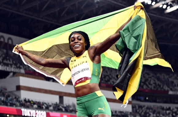 일레인 톰프슨헤라(자메이카)가 3일 2020 도쿄올림픽 육상 여자 200m를 우승하며 두 대회 연속 100m와 200m 우승을 차지하는 ‘더블더블’을 달성한 뒤 국기를 펼쳐 보이며 트랙을 돌고 있다. 도쿄 EPA 연합뉴스 