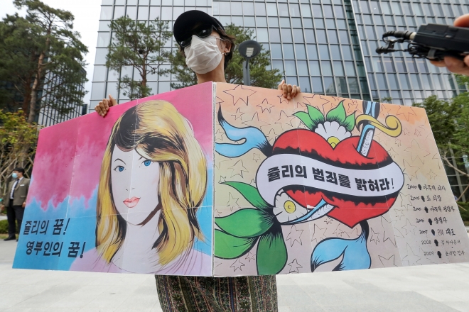 6일 오후 서울 강남의 한 호텔 앞에서 한 시민이 서울 종로구의 중고서점 담벼락에 그려졌다 지워진 ‘쥴리의 남자들’ 벽화를 닮은 피켓을 들고 1인 시위를 하고 있다. 2021.8.6 뉴스1