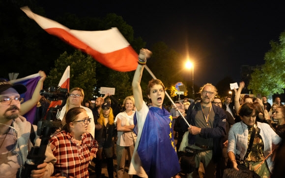 언론의 자유를 제약할 소지가 있는 새 미디어법을 폴란드 하원이 찬성 228표, 반대 216표, 기권 10표로 가결시킨 11일(현지시간) 의사당 밖에 운집한 시위대가 폴란드 깃발을 흔들며 반대 시위를 벌이고 있다. 바르샤바 AP 연합뉴스