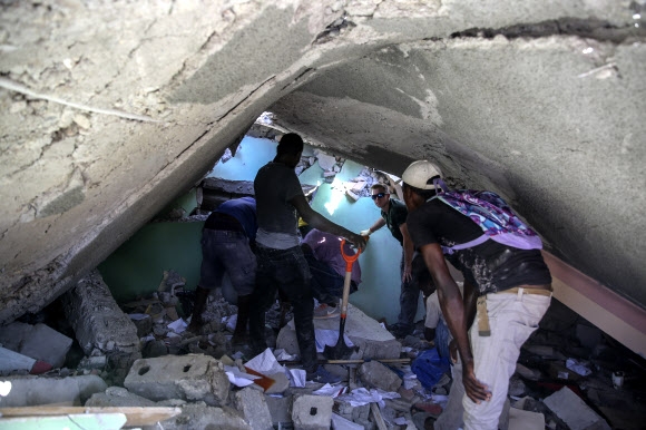 아이티 사람들이 14일 지진으로 무너진 집의 잔해에서 생존자를 찾고 있다. AP 연합뉴스.