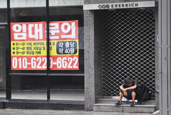 비가 내린 8월의 어느 날, 서울 종로의 임대 현수막이 붙은 텅 빈 상점 앞에 노숙인이 지친 표정으로 앉아 있다. 장기적인 코로나19의 영향으로 폐업률이 늘어 가고 있는 가운데 폐업의 위기에 몰린 자영업자들의 시름이 날로 깊어지고 있다. 박지환 기자 popocar@seoul.co.kr