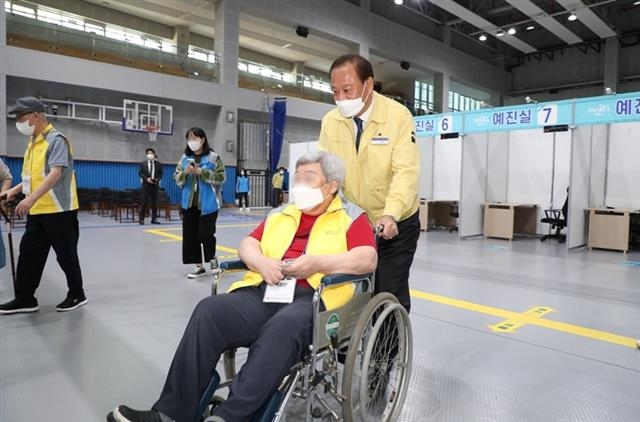 유동균(오른쪽) 서울 마포구청장이 코로나19 예방접종센터에서 휠체어를 탄 어르신의 접종을 돕고 있다. 마포구 제공