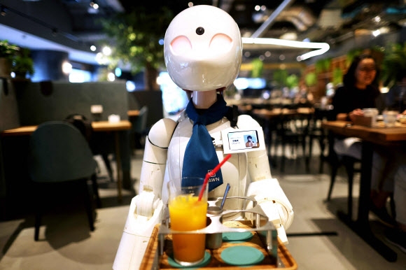 지난 17일 일본 도쿄 도운 카페에서 인간의 형태를 닮은 휴머노이드 로봇이 주문된 음료를 손님들에게 서빙하고 있다. 24일 도쿄패럴림픽 개최를 앞두고 론칭한 이 서비스에서 로봇 노동자는 이름표까지 가슴에 달았다.  도쿄 AFP 연합뉴스