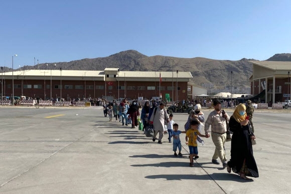 한국 정부와 협력한 아프가니스탄인들이 국내 이송을 위해 카불 공항에 도착한 한국 공군 수송기로 이동하고 있다. 2021.8.25  외교부 제공