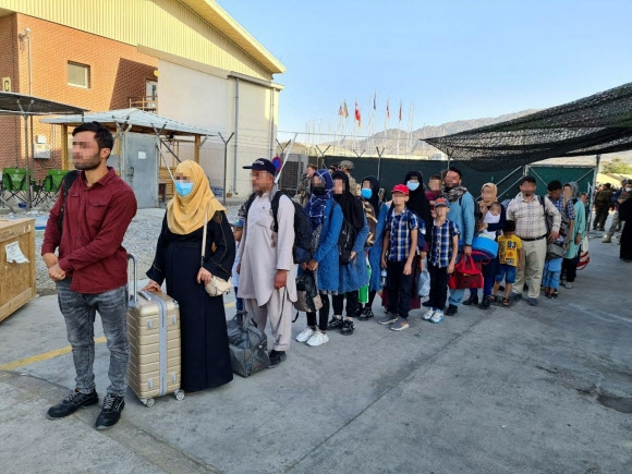 한국 정부와 협력한 아프가니스탄인들이 국내 이송을 위해 카불 공항에 도착한 한국 공군 수송기에 탑승하기 위해 줄을 서서 기다리고 있다. 2021.8.25  외교부 제공