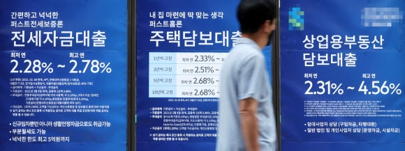 지난달 26일 한 시민이 서울 시내 은행 외벽에 붙은 대출 안내문 앞을 지나가고 있다. 연합뉴스