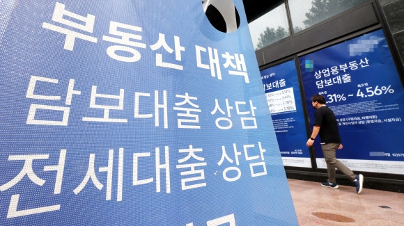 29일 서울의 한 은행지점 외벽에 걸린 대출상담 광고 앞을 한 시민이 지나가고 있다. 연합뉴스