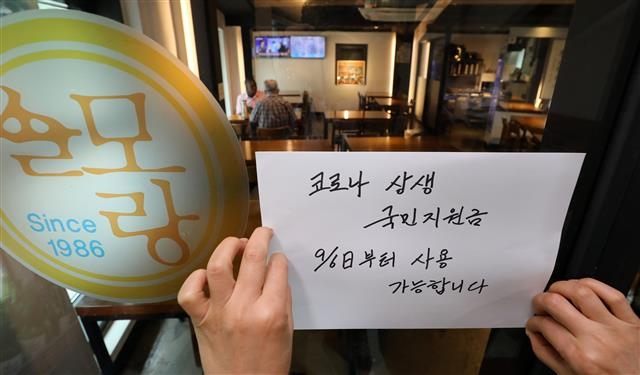 30일 서울 종로구의 한 식당에 ‘코로나 상생 국민지원금’이 다음달 6일부터 사용 가능하다는 안내문이 부착되고 있다. 뉴스1