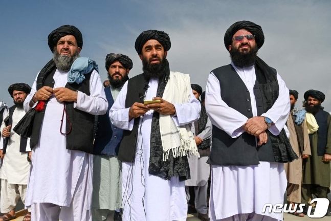 30일(현지시간) 미군이 철수한 후 자비훌라 무자히드(가운데) 탈레반 대변인은 카불공항 활주로에서 승리를 자축했다. 뉴스1