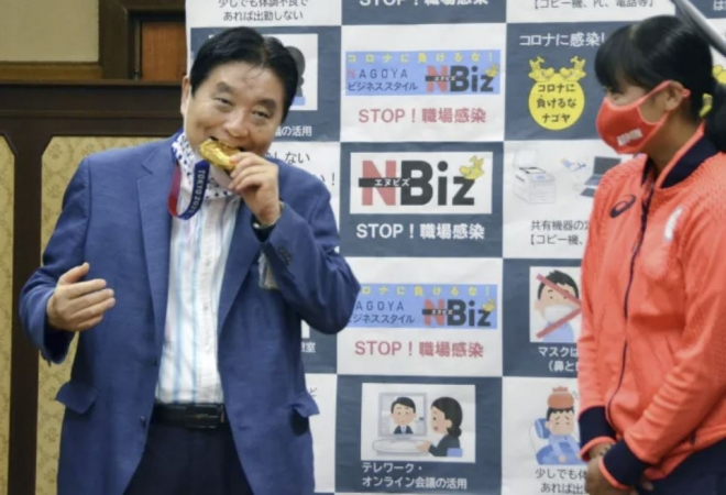 가와무라 다카시 일본 나고야 시장(왼쪽)이 지난 4일 나고야 시청을 방문한 도쿄올림픽 소프트볼 금메달리스트 고토 미우의 메달을 양해도 구하지 않은 채 깨물고 있다. 교도 연합뉴스