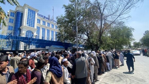 미군이 완전 철수한 뒤 이슬람 무장단체 탈레반의 아프가니스탄 통치 이틀째인 지난 1일(현지시간) 카불 시내 한 은행 앞에 돈을 찾으려는 사람들이 길게 늘어서 있다.  카불 EPA 연합뉴스
