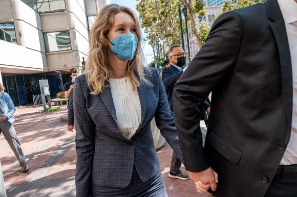 혈액 진단 기기를 개발했다며 스타트업 기업 ‘테라노스’를 창업했다가 희대의 사기꾼으로 내몰린 엘리자베스 홈즈가 8일(현지시간) 캘리포니아주 새너제이 지방법원에서 3년 만에 재개된 재판의 모두 진술에 참석하기 위해 남편 빌리 에반스의 손을 잡고 들어가고 있다. 새너제이 AFP 연합뉴스 