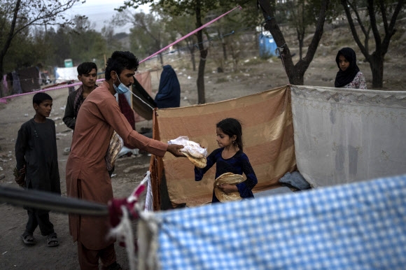 아프가니스탄 수도 카불의 난민촌에서 13일(현지시간) 구호단체 직원들이 어린이에게 식량을 나눠 주고 있다. 지난달 탈레반이 아프간 외곽 지역부터 장악함에 따라 카불로 몰려들었던 실향민들은 탈레반이 아프간 전체를 점령하고, 미군이 철수한 이후에도 카불 난민촌에 남아 있다. 국제사회는 아프간에 1조원 이상 인도적 지원을 약속했다. 카불 AP 연합뉴스