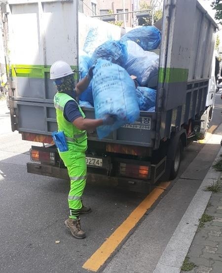 서울 마포구의 한 환경미화원이 100ℓ 쓰레기 종량제 봉투를 수거 차량에 싣고 있다. 마포구는 환경미화원의 안전한 근무 환경을 조성하기 위해 100ℓ 종량제 봉투 제작을 중단하기로 했다. 마포구 제공