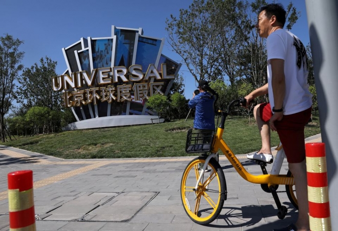 중국 베이징의 한 시민이 공유 자전거를 타고 유니버셜 스튜디오 간판 앞을 지나가고 있다. 로이터 연합뉴스