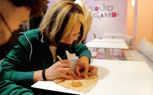 프랑스 파리에 마련된 ‘오징어 게임’ 체험 팝업 스토어에서 한 관람객이 설탕 뽑기 게임에 집중하고 있다. 넷플릭스 프랑스 제공