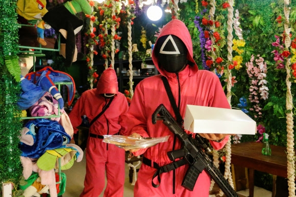 인도네시아 자카르타에 등장한 드라마 ‘오징어 게임’을 주제로 한 카페에서 드라마 속 복장을 입은 카페 웨이터들이 달고나를 나르고 있다. 로이터 연합뉴스