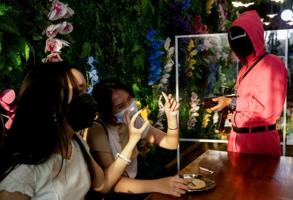 인도네시아의 한국 드라마 ‘오징어 게임’을 주제로 한 카페에서 손님들이 달고나 게임을 즐기고 있다. 로이터 연합뉴스