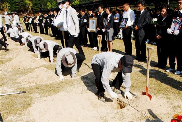 유족들이 지켜보는 가운데 행사 요원들이 묘역을 조성하고 있다.  국립대전현충원 제공