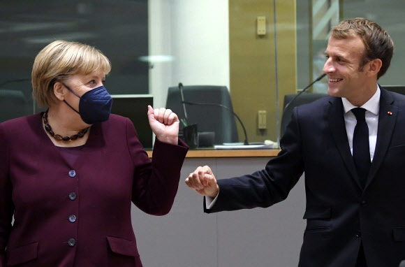 독일 총리 직을 물러나기 전에 유럽연합(EU)의 마지막 정상회의에 참석한 앙겔라 메르켈(왼쪽)이 22일(현지시간) 에마뉘엘 마크롱 프랑스 대통령과 주먹을 맞대며 웃고 있다. 브뤼셀 풀 기자단 AP 연합뉴스