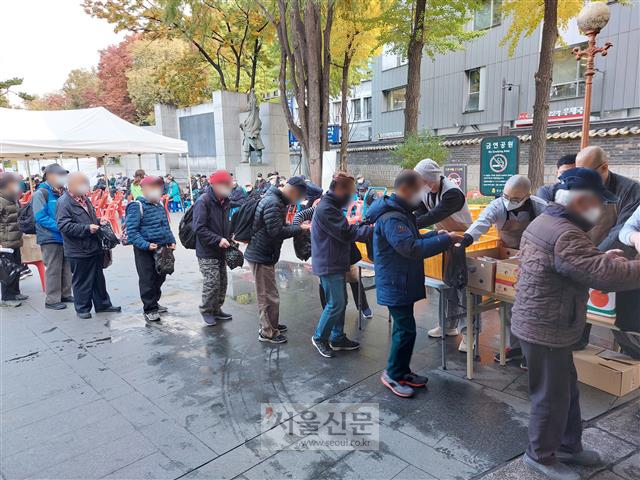 서울 종로구 탑골공원에서 2일 노인들이 무료로 지급되는 도시락을 미리 받아 놓았던 검은색 비닐봉지에 받고 있다. 탑골공원 정문인 삼일문 앞에서 진행된 무료 급식은 30분도 안 돼 종료됐다. 오세진 기자 5sjin@seoul.co.kr