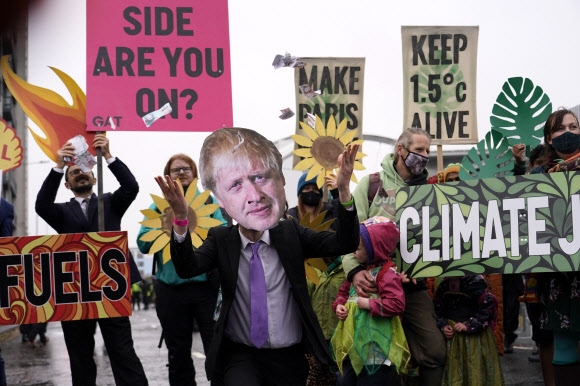 지난 12일(현지시간) 영국 글래스고에서 열린 제26차 유엔기후변화협약 당사국총회(COP26) 회의장 밖에서 보리스 존슨 영국 총리의 가면을 쓴 기후운동가가 화석연료 사용에 반대하는 시위를 벌이고 있다. 글래스고 AP 연합뉴스