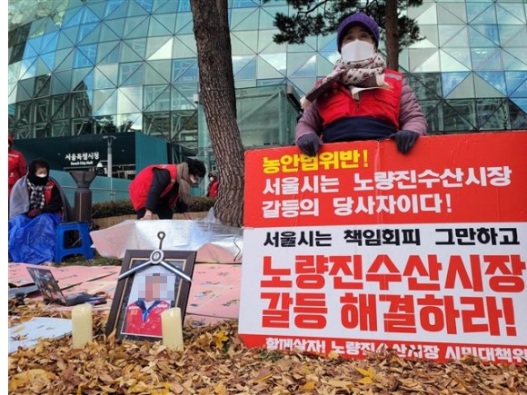 노량진수산시장 상인들이 22일 서울시청 앞 공터에서 노량진수산시장 현대화 사업 반대 농성에 참여했다 사망한 나세균씨의 영정사진 앞에서 피켓 시위를 하고 있다.