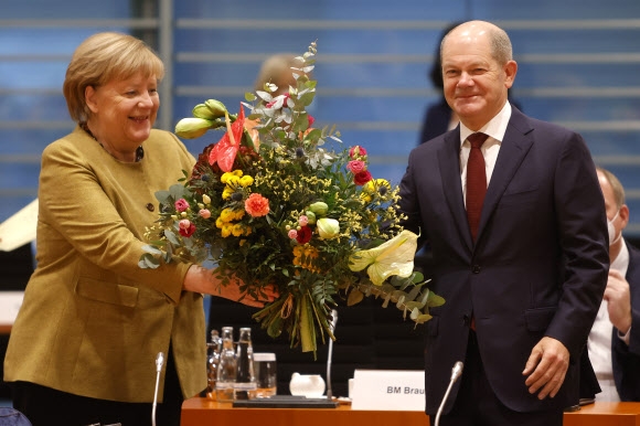 앙겔라 메르켈(왼쪽) 독일 총리 대행이 24일(현지시간) 수도 베를린에서 각료회의가 시작되기 전 사회민주당(SPD) 소속 올라프 숄츠 차기 총리로부터 꽃다발을 받고 있다. 사회민주당·녹색당·자유민주당(FDP)이 새 연립 정부 구성을 위한 합의에 도달하면서 16년간 독일을 이끈 ‘메르켈 체제’가 끝나고 숄츠 정부가 바통을 이어받게 된다. 베를린 EPA 연합뉴스