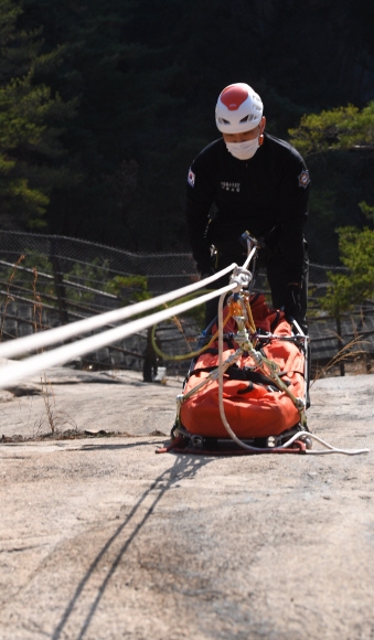 북한산의 낭떠러지에서 산악구조대 소속 송한준 소방교가 들것을 로프에 묶어 옮기는 훈련을 하고 있다.