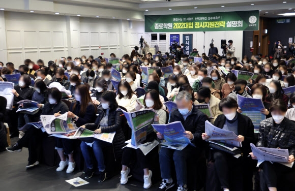 대학수학능력시험 직후인 지난 19일 서울 광진구 건국대 동문회관에서 열린 2022학년도 대입 정시지원 설명회에서 학생과 학부모들이 자료를 들춰 보며 입시업체의 설명을 듣고 있다. 연합뉴스