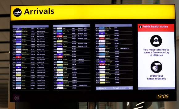 30일(현지시간) 영국 런던 히드로공항의 스크린에 항공편 정보와 함께 코로나19 방역수칙이 표시되고 있다. 영국은 지난 28일부터 남아프리카공화국을 포함한 ‘레드 리스트’ 국가에서 자국에 도착하는 승객의 경우 10일간 격리될 정부 승인 호텔을 자비로 예약하도록 하고 있다. 런던 신화 연합뉴스