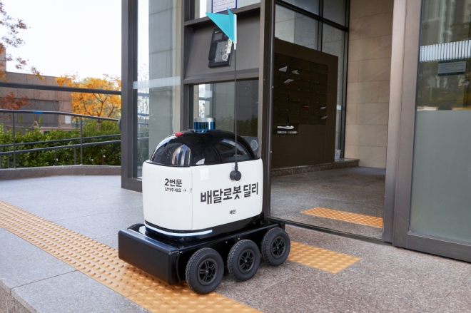 자율주행 배달 로봇 ‘딜리드라이브’가 경기도 수원 광교 앨리웨이에서 음식 배달을 위해 아파트 공동현관을 통과하고 있는 모습. 우아한형제들 제공.