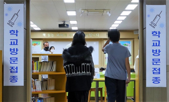 16일 부산 부산진구에 있는 한 초등학교 도서관에서 ‘찾아가는 백신접종’을 신청한 6학년 학생들이 코로나19 백신 접종을 하기 위해 대기하고 있다. 부산 연합뉴스