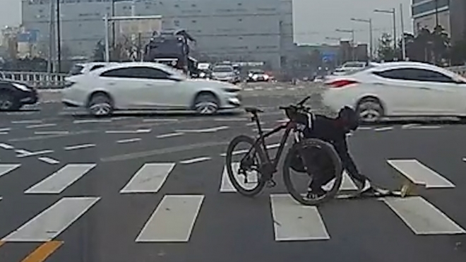 한 자전거 라이더가 횡단보도를 건너다 박스를 주워들고 있다. 보배드림 제공.