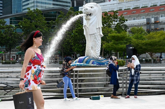 28일(현지시간) 싱가포르의 머라이언 동상 앞을 사람들이 지나고 있다. 싱가포르 AFP 연합뉴스