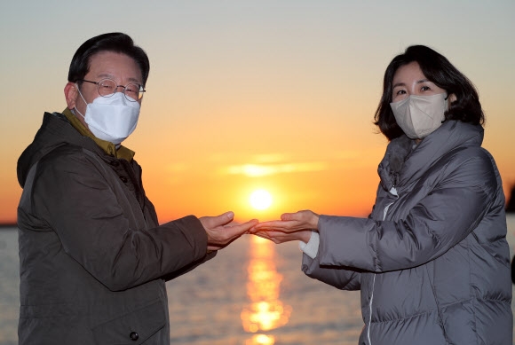 더불어민주당 이재명 대선후보가 부산경남 방문 이틀째인 2일 부산시 사하구 다대포해수욕장에서 부인 김혜경씨와 함께 ‘2022 글로벌 해돋이 : 지구 한 바퀴’ 온라인 해맞이 행사에서 떠오르는 태양을 손 위에 올려 놓는 포즈를 취하고 있다. 2022.1.2 연합뉴스