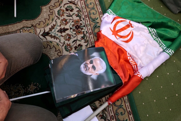 거셈 솔레이마니 이란 혁명수비대(IRGC) 쿠드스군 사령관 사망 2주기인 3일(현지시간) 추모식이 열린 이란 수도 테헤란 무살라 모스크에서 한 남성이 솔레이마니의 초상화 앞에 무릎을 꿇고 있다. 테헤란 AFP 연합뉴스