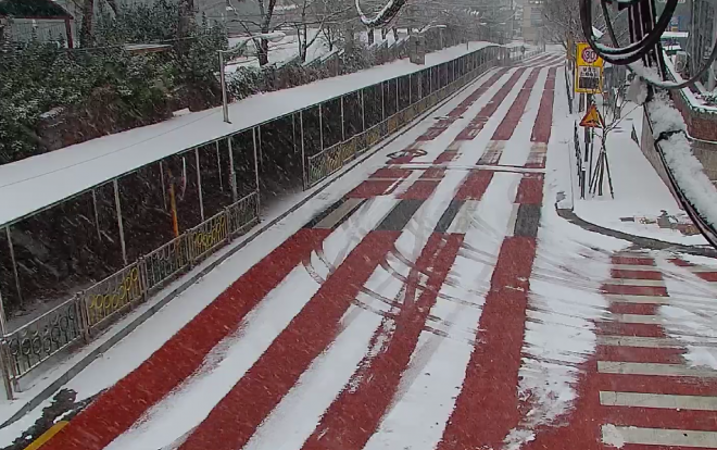 서울 성북구 정릉동 정수초등학교 인근 경사로에 눈이 내렸지만 도로 아래에 친환경 열선 시스템을 설치한 덕분에 열선이 지나는 곳에는 눈이 녹아있다. 성북구 제공 