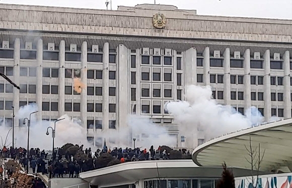 액화석유가스(LPG) 가격 인상에 반대하는 대규모 시위가 카자흐스탄 곳곳에서 일어난 가운데 5일(현지시간) 최대 도시 알마티의 연기가 피어오르는 시청사 근처에 시위대가 운집해 있다. 2022.1.5 AFP 연합뉴스