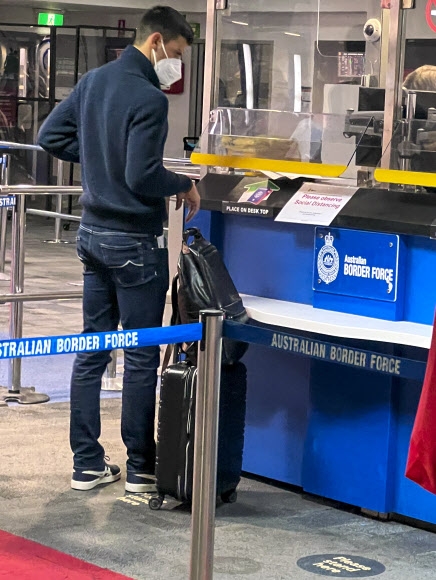 테니스 스타 노바크 조코비치(세르비아)가 지난 5일 호주 멜버른 국제공항에 도착한 뒤 출입국관리소에서 입국 비자가 찍힌 여권이 돌아오길 기다리며 서 있다. 그가 멜버른에 도착한 모습의 사진으로는 8일에야 처음 공개된 것이다. 그가 세르비아에서 비행기를 탈 때만 해도 백신 면제 요건을 충족해 입국 비자가 나올 것이라는 호주오픈 테니스대회 조직위원회의 연락을 받았으나 이곳에서 입국 비자가 취소됐다는 청천벽력 같은 소식을 듣고 지금껏 정부 격리 호텔에 사실상 감금돼 10일 법원 판결을 초조히 기다리고 있다. 멜버른 AP 연합뉴스 