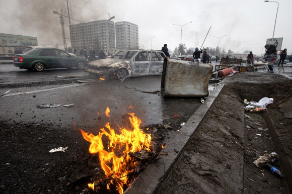 7일(현지시간) 카자흐스탄 알마티의 한 거리에서 사람들이 반정부 시위와 진압 과정에서 불에 탄 자동차 앞을 지나가고 있다. 알마티 AP 연합뉴스