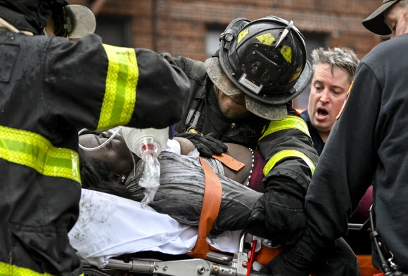 9일(현지시간) 미국 뉴욕 브롱크스의 19층짜리 아파트에서 화재가 발생한 가운데 소방대원들이 부상자를 들것에 태워 구급차로 옮기고 있다. AP 연합뉴스