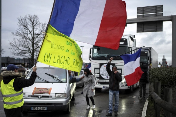 11일(현지시간) 프랑스 중부 리옹에서 코로나19 백신 접종 의무화에 반대하는 시위대가 트럭 앞에서 대형 프랑스 국기를 흔들고 있다. 파리 경찰청은 공공질서 유지를 이유로 도로 봉쇄를 목적으로 한 시위를 금지했다. 리옹 AP 연합뉴스