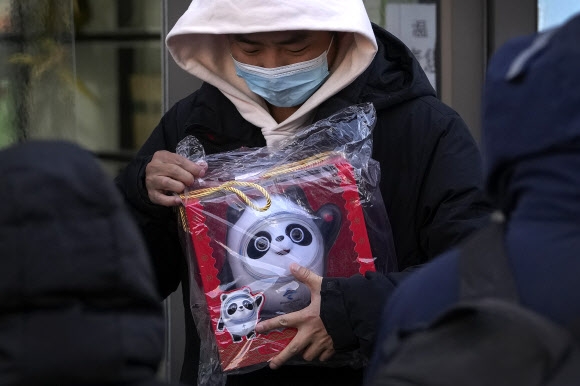 한 남성이 2022 베이징 동계올림픽 기념품 가게에서 빙둔둔 인형을 들고 있는 모습. 2022.02.14 AP 연합뉴스 
