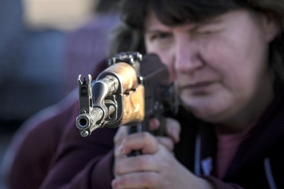 13일(현지시간) 우크라이나 동부 도네츠크주 마리우폴에서 한 여성이 우크라이나 국가방위군 산하 아조프 부대가 주관한 민간인을 위한 기초 전투 훈련에 참가해 소총을 겨누고 있다. 마리우풀 AP 연합뉴스