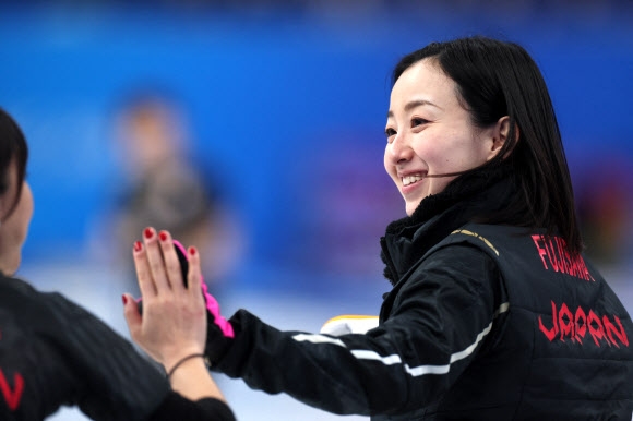 ‘팀 후지사와’의 후지사와 사츠키가 18일 중국 베이징 국립 아쿠아틱센터에서 열린 2022 베이징동계올림픽 컬링 준결승에서 미소 지으며 하이파이브하고 있다. 베이징 로이터 연합뉴스