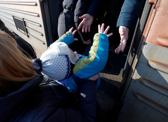 친러 반군 통제 지역에서 피란 열차 오르는 우크라 어린이 23일(현지시간) 친(親)러시아 반군이 통제하는 우크라이나 동부 도네츠크의 마키이우카에서 피란길에 오른 주민이 어린이를 열차에 태우고 있다. 우크라이나 동부 돈바스 지역 반군이 세운 도네츠크인민공화국(DPR)과 루간스크인민공화국(LPR)은 최근 대피령을 내려 수만 명의 주민이 러시아로 피란 중이다. 2022.2.24 마키이우카 로이터 연합뉴스