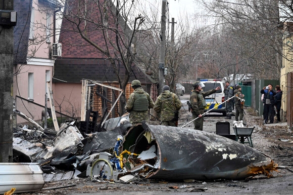 우크라이나 군인들이 25일(현지시간) 키예프의 주택에 추락한 미확인 항공기 잔해를 조사하고 있다. AFP 연합뉴스
