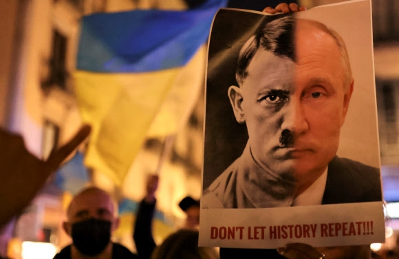 24일(현지시간) 스페인 바르셀로나에서 열린 우크라이나 지지 시위에서 한 참가자가 블라디미르 푸틴 러시아 대통령과 나치 독일의 독재자 히틀러의 얼굴을 합성한 사진을 들고 있다. 바르셀로나 로이터 연합뉴스