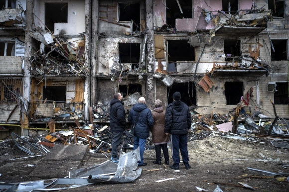 우크라이나 시민들이 러시아의 공격으로 무너진 건물을 바라보고 있다. 2022.02.25 AP 연합뉴스